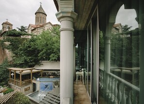 Une vue d’un bâtiment avec une piscine, un patio couvert et une église en arrière-plan.