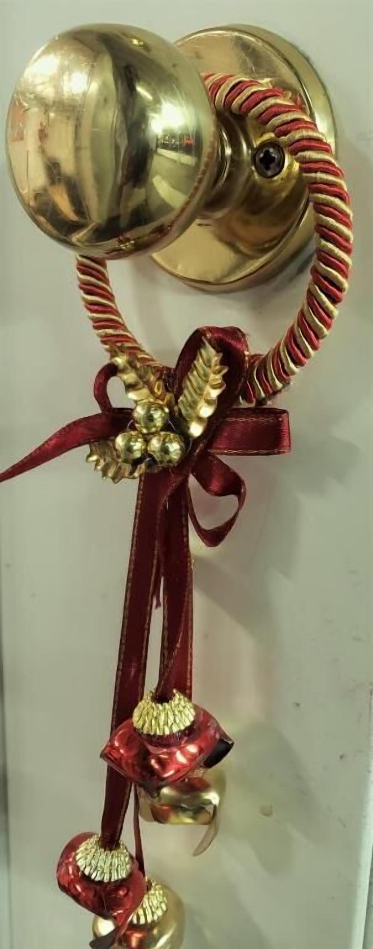 A door knocker with a shiny metallic finish, a red ribbon, and a decorative bow.