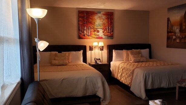 Habitación de hotel con dos camas, una mesita de noche con lámparas, un cuadro en la pared y una silla.