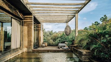 Un espace piscine extérieur abrité, doté d’un nid suspendu et entouré d’une végétation luxuriante.