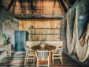 A rustic kitchen with wooden shelves, a dining table, and chairs.