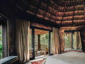 A room with a bed, large windows, curtains, and a thatched roof. - Nômade Temple Tulum (Tulum)