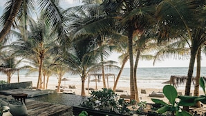 A beach resort with palm trees, lounge chairs, and a pool area. - Nômade Temple Tulum (Tulum)