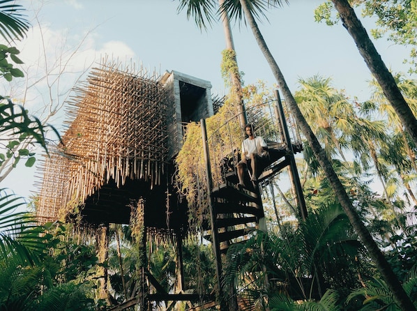 Une construction à toit de chaume avec un escalier menant à une plateforme.