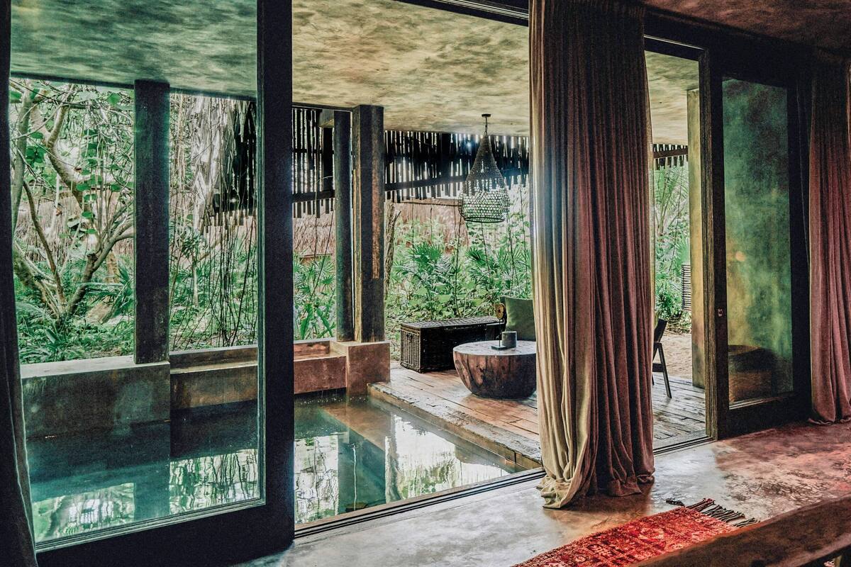 Una habitación con ventanas amplias, un elemento decorativo de agua y vistas al verdor exterior.