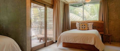 A bedroom with a large bed, a wooden headboard, and a view through a glass door to an outdoor area.