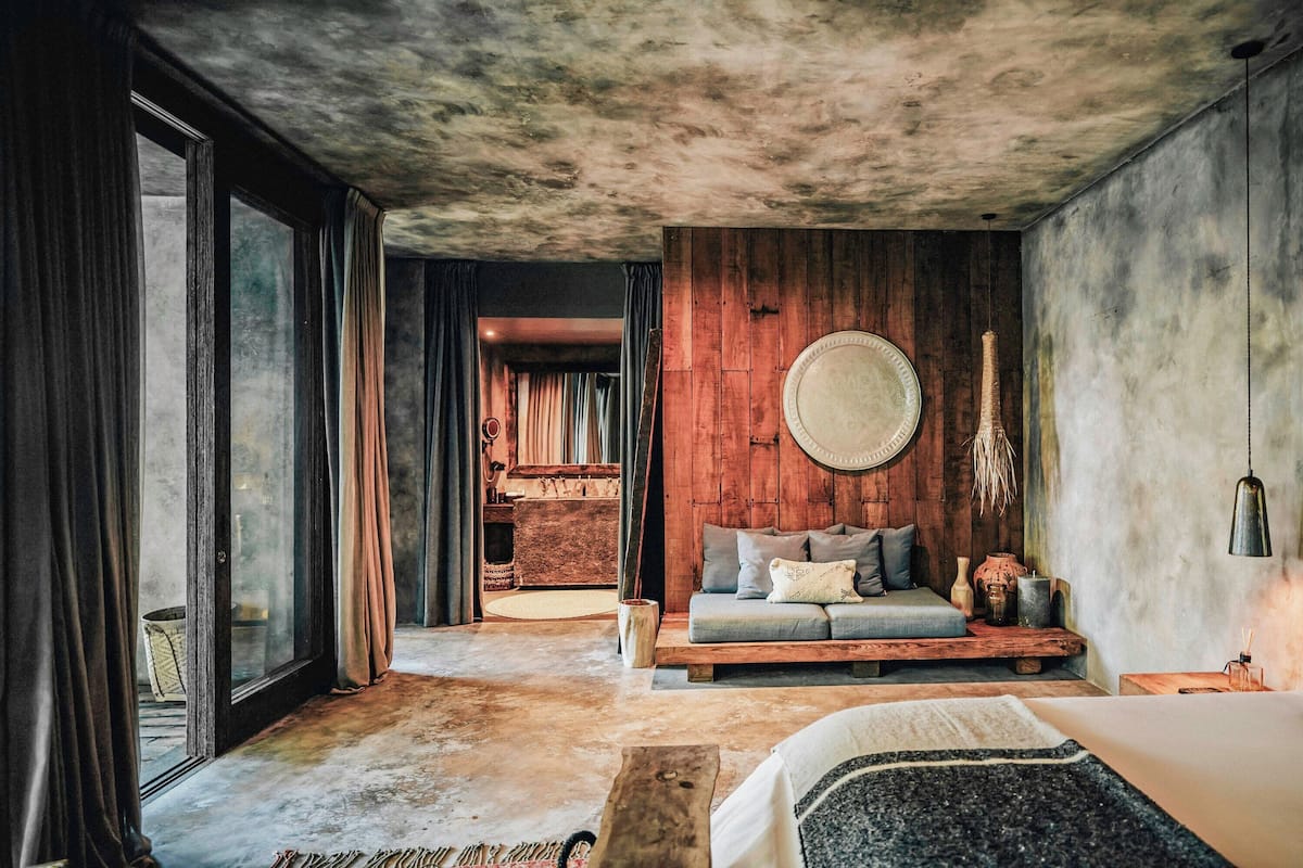 Una habitación con una cama grande, un sofá, un adorno circular en la pared y un banco de madera.