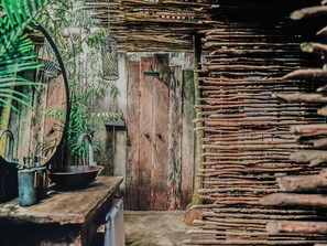 A rustic wooden door, a hanging light fixture, and a woven wall structure.