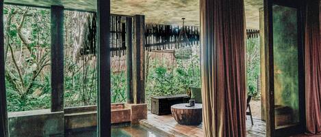 A room with large windows, a water feature, and a view of greenery.