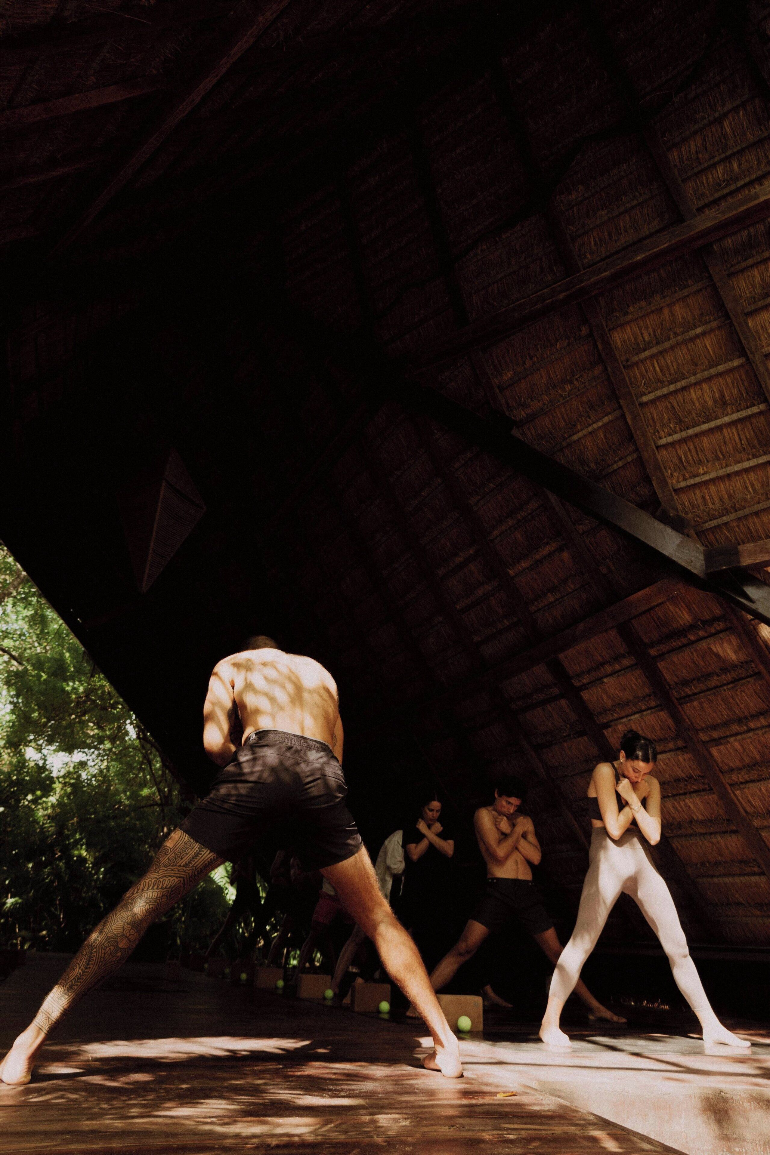 A group of people in a covered area with a wooden ceiling and a concrete floor.