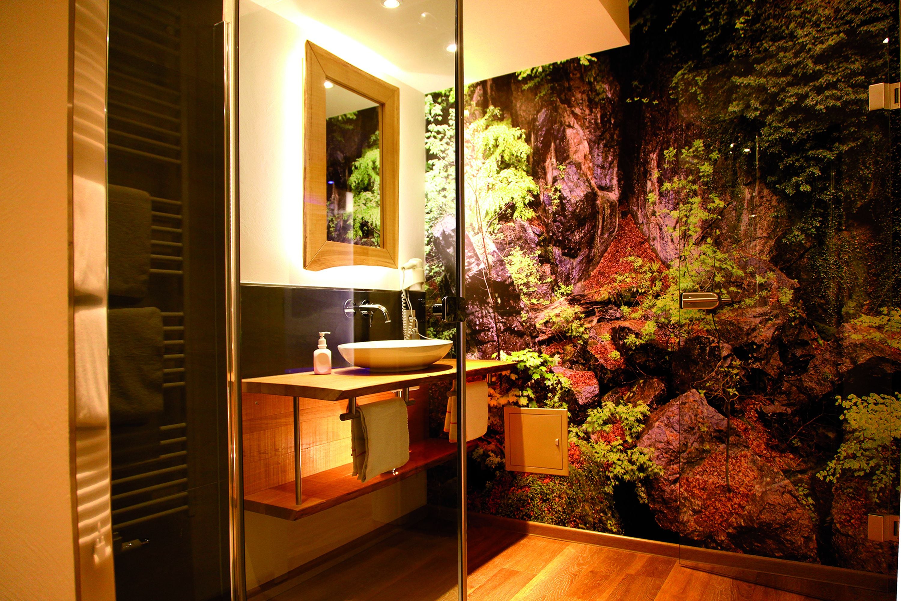 A bathroom with a large mirror, a sink, and a wall-mounted cabinet.