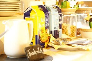 A breakfast setup with a coffee maker, cereal boxes, and a plate of food. - Flair Hotel Nieder (Bestwig)