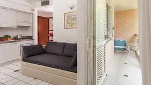 A modern kitchen with white cabinets, a sofa, and a dining area with a table and chairs. - Residence Villa Lidia (Riccione)