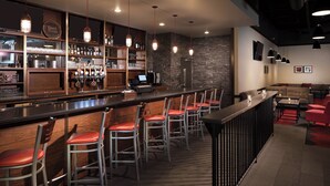A bar area with a long counter, multiple stools, and a seating area with couches and tables.