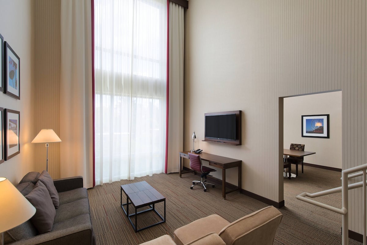 Une chambre d’hôtel avec un canapé, un bureau avec un ordinateur, une télévision et une petite table.