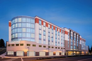 Een modern hotelgebouw met een gebogen glazen gevel, meerdere verdiepingen en een plat dak.