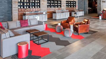 A modern lobby with a sofa, armchairs, a coffee table, and a reception desk.