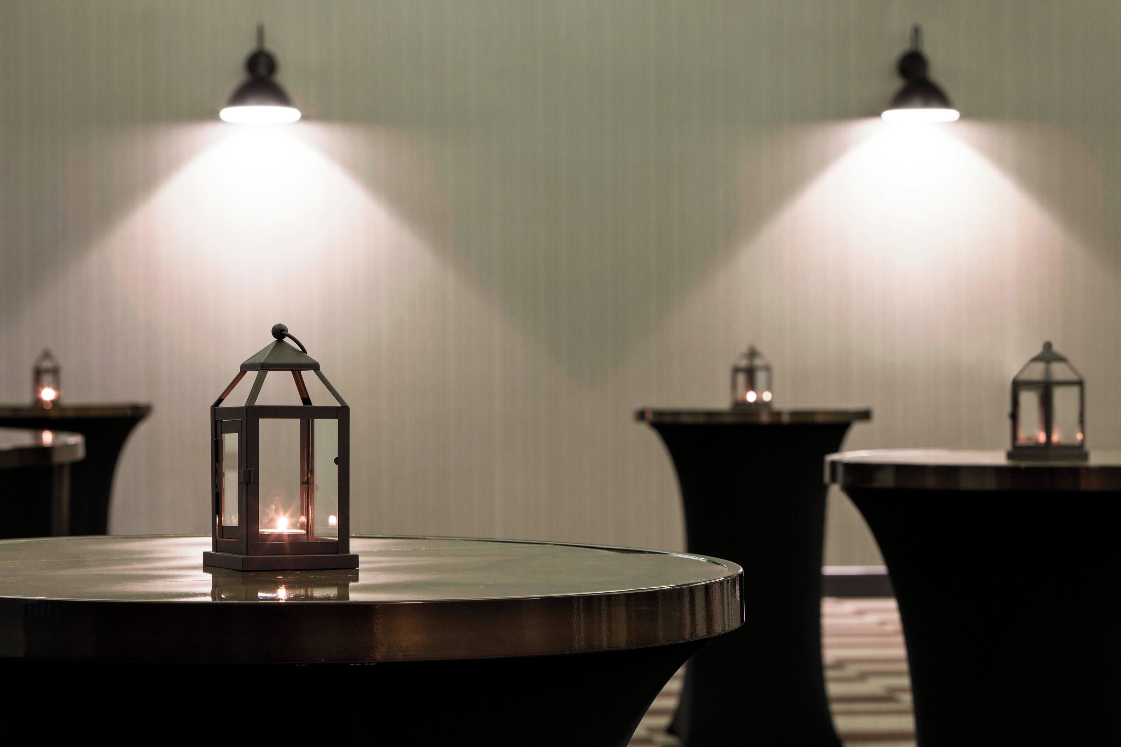 Varias mesas con lámparas de estilo farol en una habitación con poca luz.