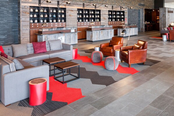 Un vestíbulo moderno con sofá, sillones, una mesa de centro y una zona de bar con estanterías.