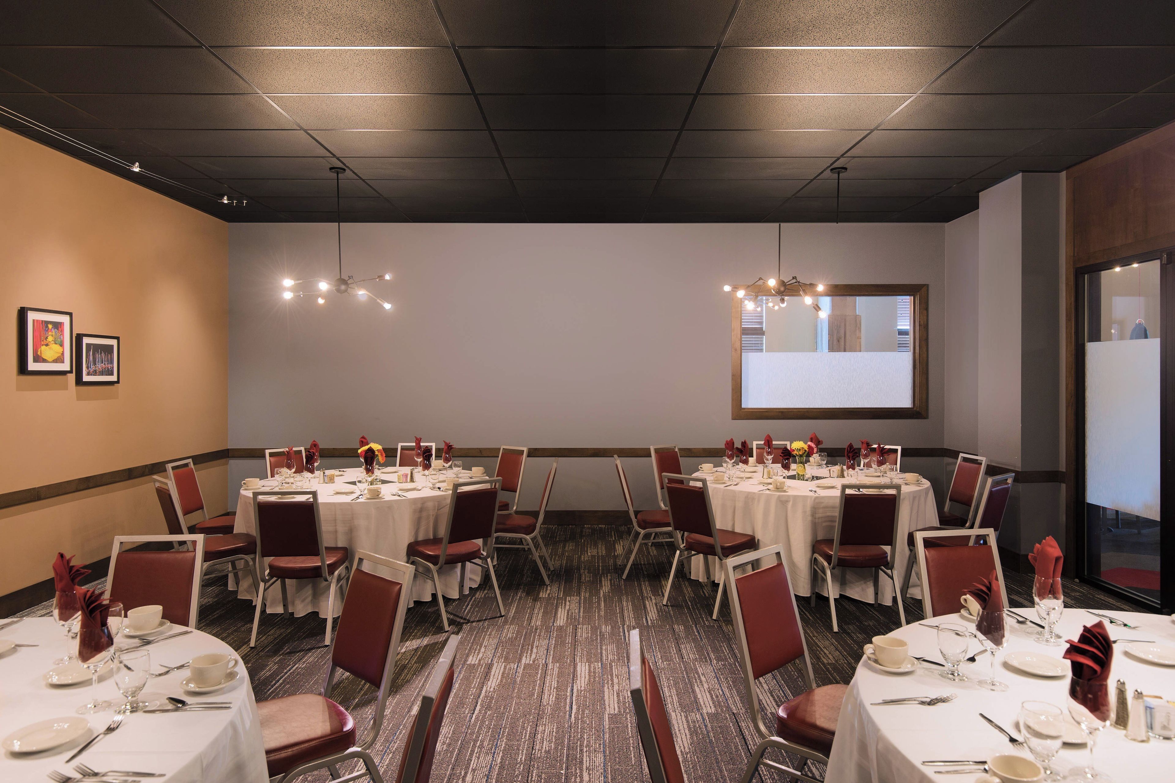 A conference room with multiple tables set for dining, equipped with chairs, tables, and centerpieces.