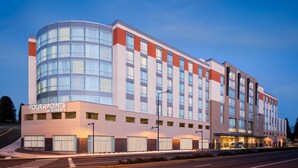 A modern hotel with a curved glass facade, multiple floors, and a prominent entrance.