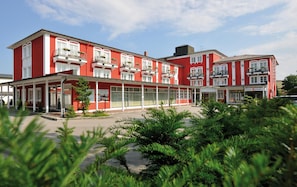 A red building with multiple balconies and a covered entrance area. - Johannesbad Hotel Füssinger Hof (Bad Fuessing)