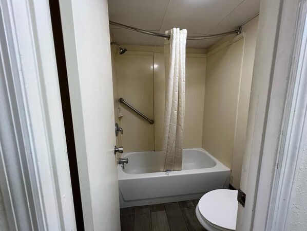 Une salle de bain avec une baignoire, des toilettes et un rideau de douche.