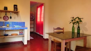 Una cocina compacta con encimera azul, una mesa de madera y dos botellas verdes sobre la mesa.