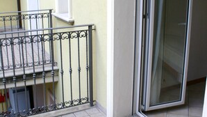 A balcony with a metal railing, a sliding glass door, and a tiled floor. - Residenza Kenzia (Cattolica)
