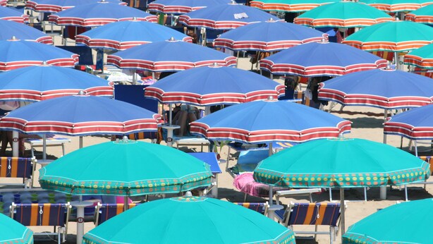 A beach with numerous umbrellas and lounge chairs arranged in rows. - Residenza Kenzia (Cattolica)