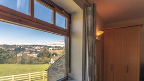 A room with a large window overlooking a scenic landscape, a wooden wardrobe, and a small shelf with a candle. - The Holly Hill Inn (Richmond)