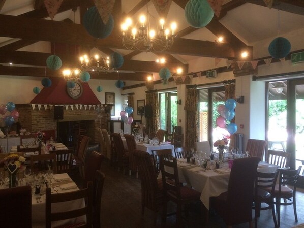 A dining area with tables set for a meal, a clock on the wall, and a red chimney.