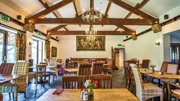A restaurant with wooden beams, a chandelier, and a large painting on the wall.