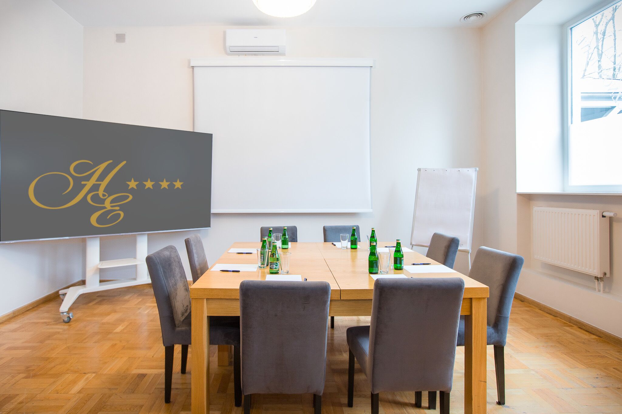 A conference room with a large table, chairs, a whiteboard, and a projector screen.