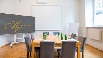 A conference room with a large table, chairs, a whiteboard, and a projector screen.