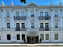 Un edificio histórico con un estilo arquitectónico europeo clásico, que presenta una fachada simétrica, balcones ornamentales y una entrada destacada con la leyenda 