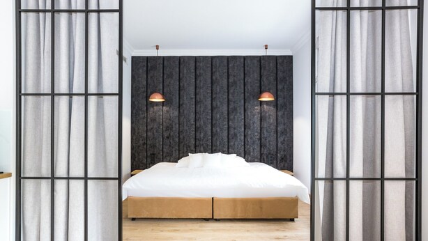 A bedroom with a bed, curtains, a headboard, and pendant lights. - Europejski Boutique Hotel (Radom)