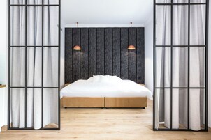 Un dormitorio con cama, cortinas, cabecero y lámparas colgantes.