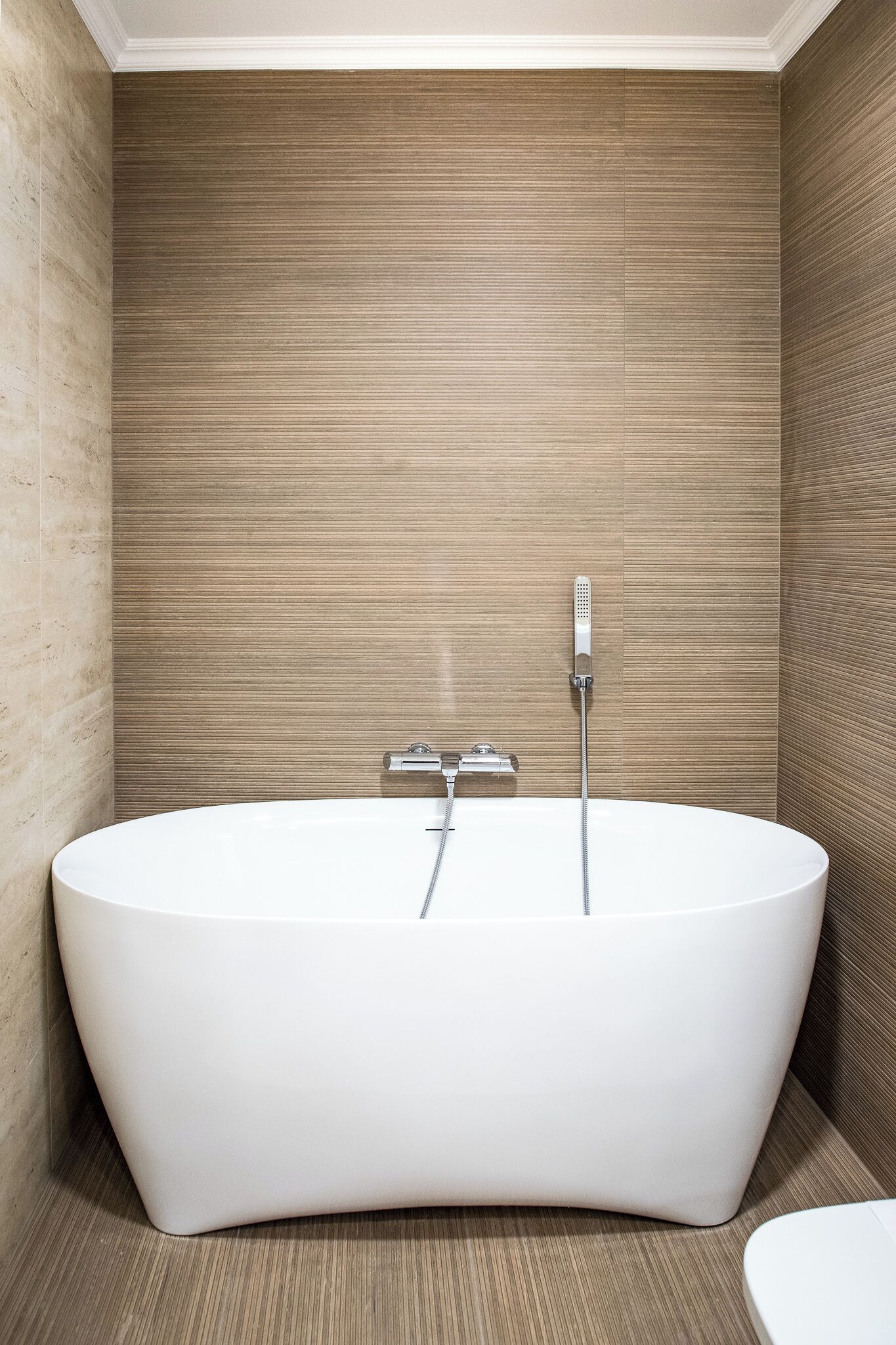 Een moderne badkamer met een vrijstaand bad, een handdouche en een toilet.
