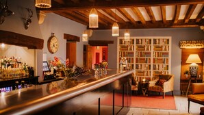 Un espace bar avec un long comptoir, une horloge et une bibliothèque en arrière-plan.