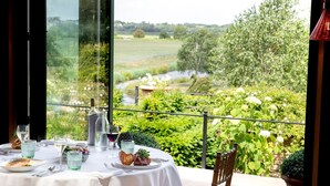 A table set for a meal with a view of a lush garden and a river. - The Old Hall Ely (Ely)