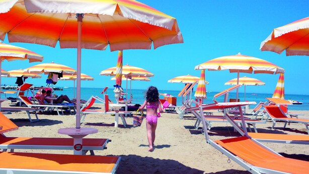 A beach with multiple sun umbrellas and lounge chairs. - Residenza Manuela (Riccione)