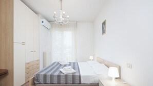 A bedroom with a bed, bedside table, lamp, and wardrobe. - Residenza Manuela (Riccione)