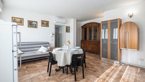 A dining area with a round table set for four, a sofa, and a cabinet with glass doors. - Residenza Manuela (Riccione)
