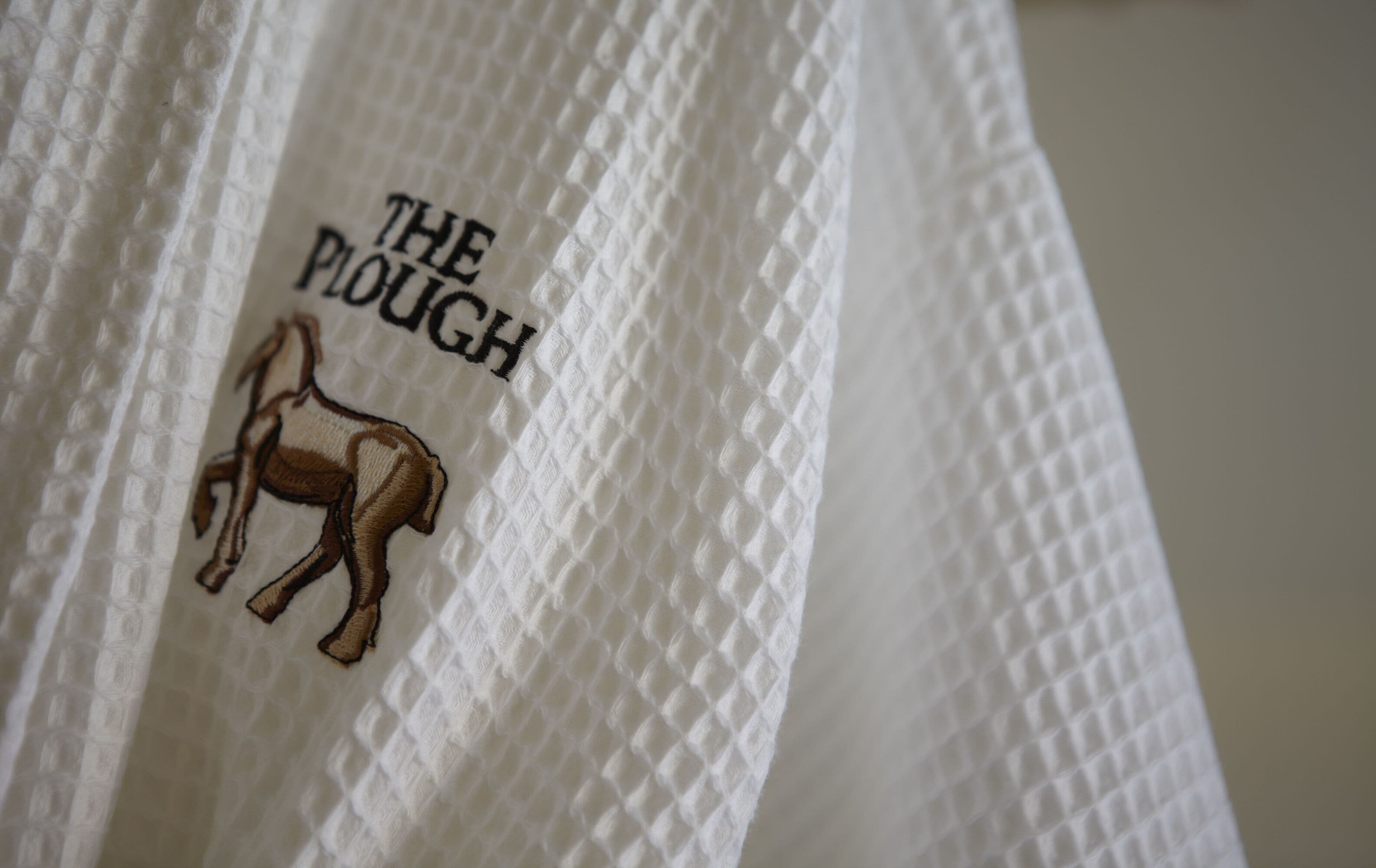 A close-up of a white textured fabric with embroidered text and a horse design.
