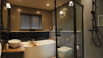 A modern bathroom with a freestanding bathtub, a toilet, and a glass-enclosed shower area.