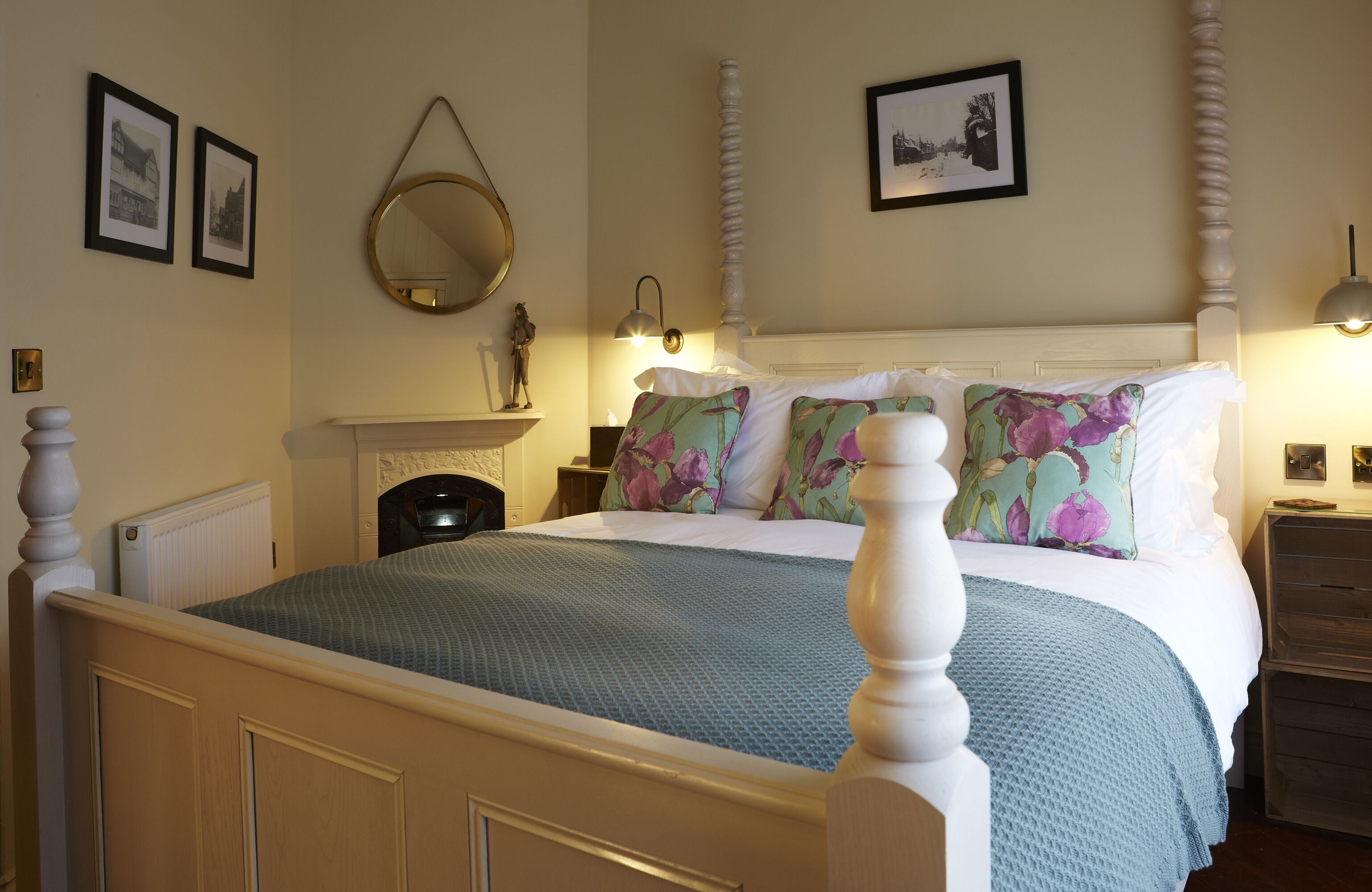 Een netjes ingerichte slaapkamer met een groot bed, een open haard en ingekaderde foto's aan de muur.