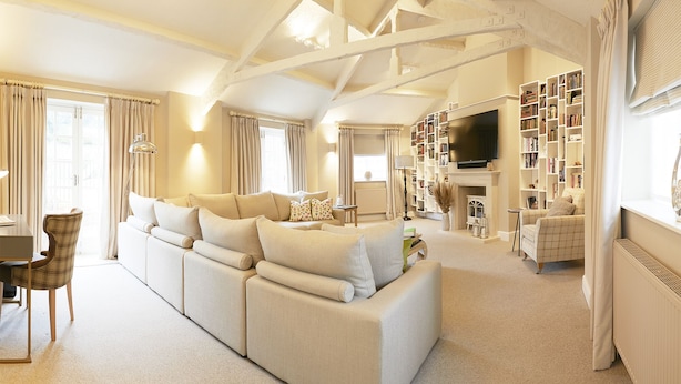 A spacious living room with a large sofa, a fireplace, a television, and a bookshelf filled with books. - The Plough Scalby (Scarborough)