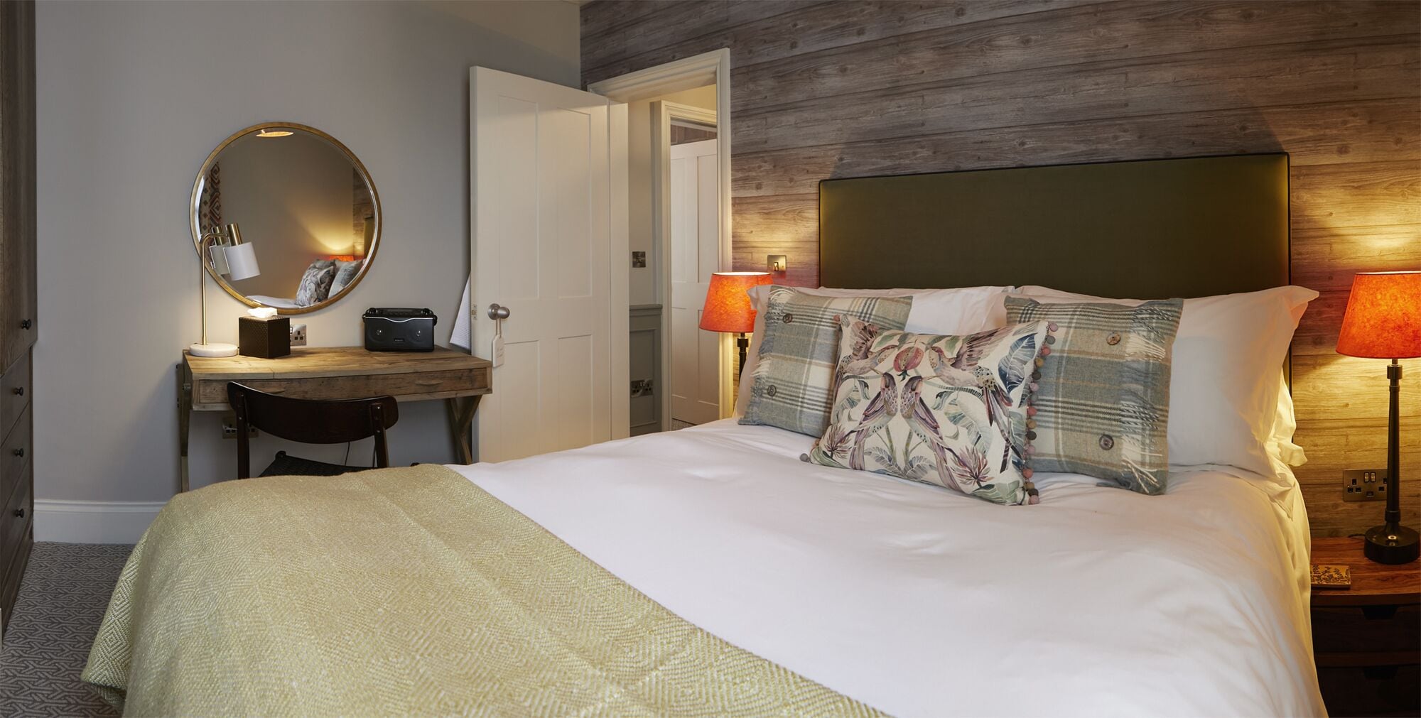 Une chambre d’hôtel comprenant un lit, un bureau, une chaise, un miroir et deux lampes.