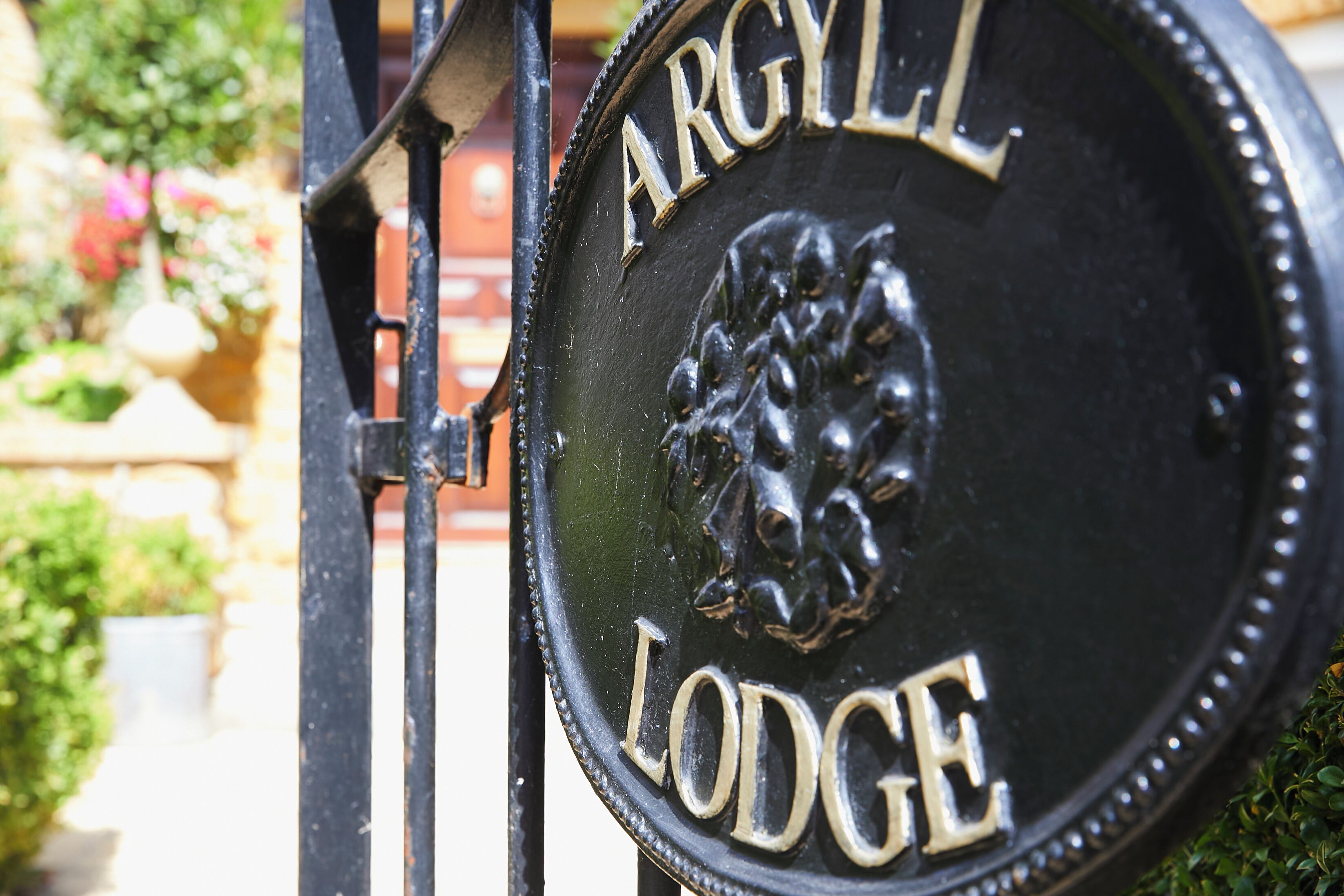 A metal sign with the inscription 'Argyll Lodge' and a lion emblem, mounted on a gate.